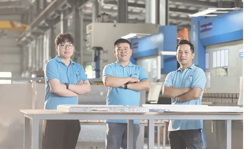 Three E-ZONG staff in blue uniforms stand at a workbench in the production base, representing the company’s supply chain capacity to meet market demands.
