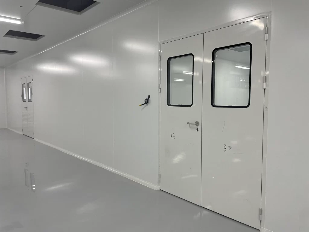 Airtight double doors with vision windows for ISO 5+ medical cleanrooms, designed to maintain sterility and controlled airflow in operating rooms/pharmacies.