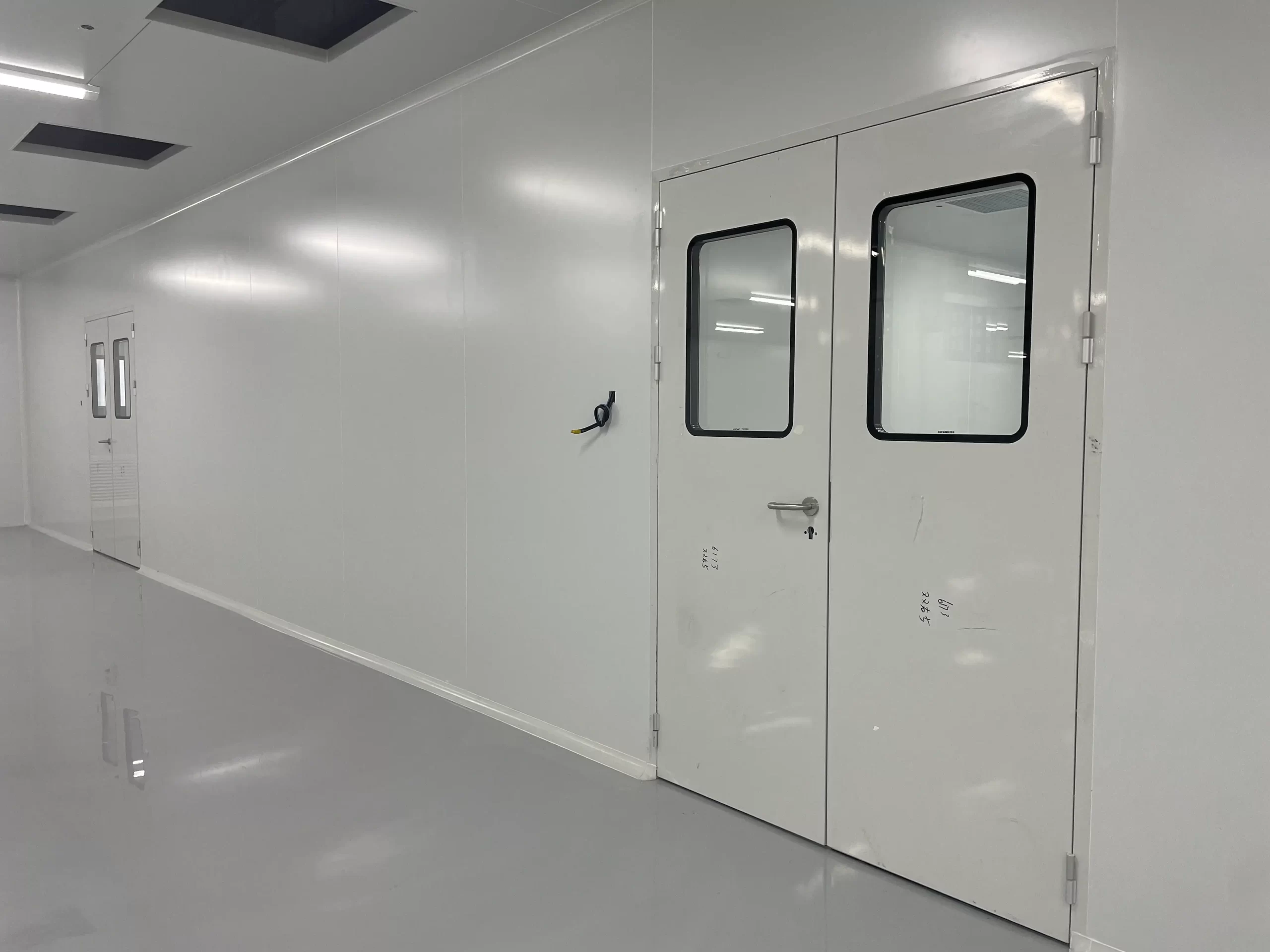 Airtight double doors with vision windows for ISO 5+ medical cleanrooms, designed to maintain sterility and controlled airflow in operating rooms/pharmacies.