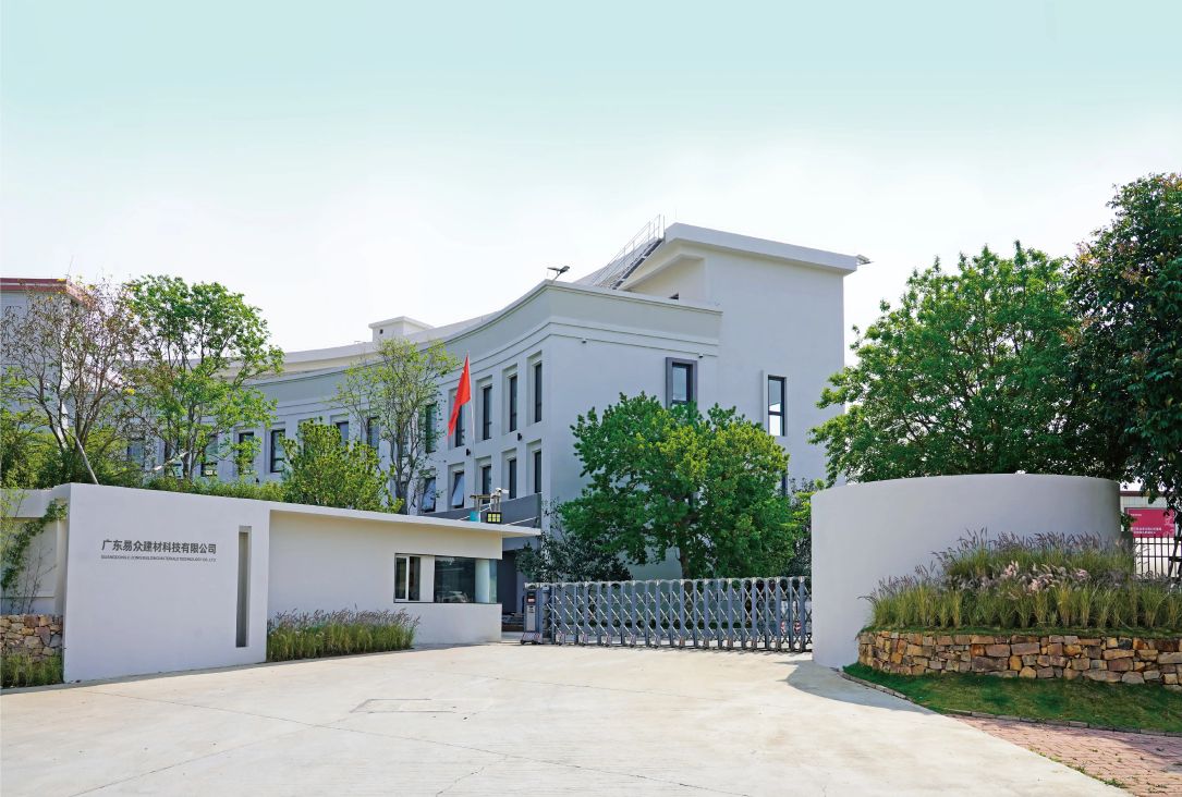 the exterior view of guangdong e-zong building materials technology co., ltd, showing a white building surrounded by greenery, with a clear entrance gate and company logo, presenting a tidy external environment for the enterprise.
