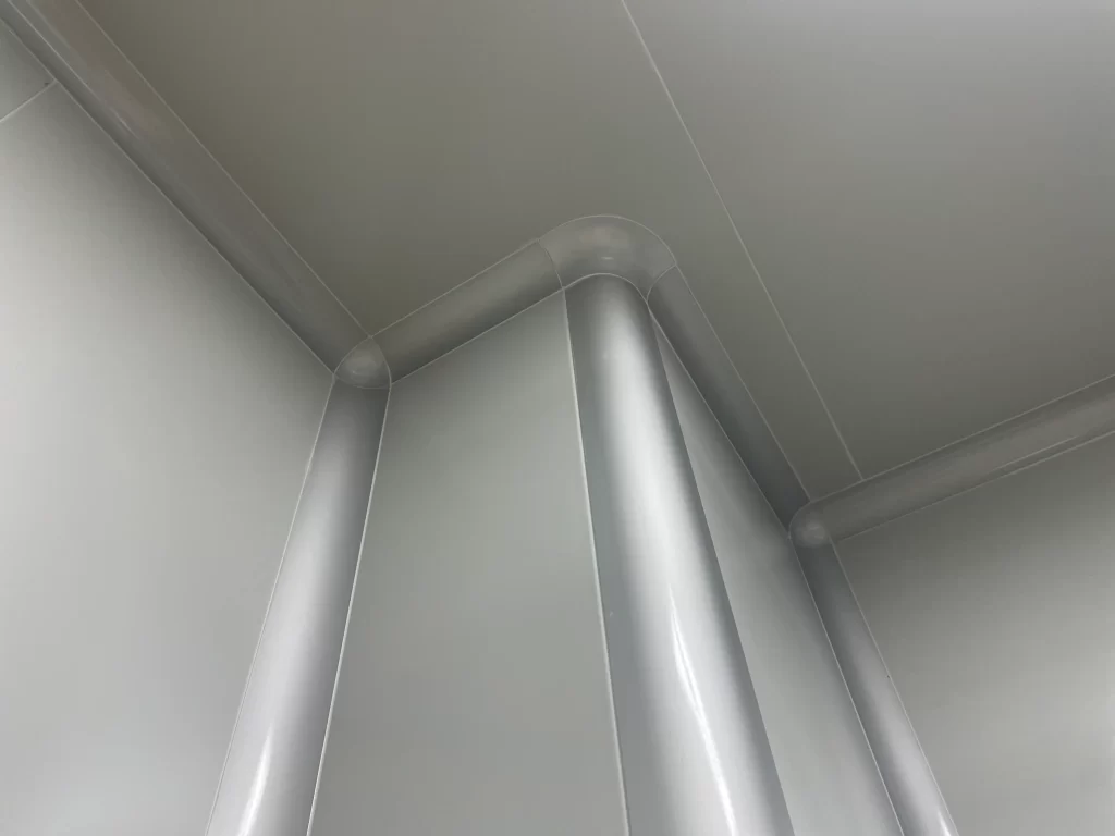 Arc - transition design at the corner of a hospital cleanroom wall and details of stainless - steel edge wrapping. It shows the seamless antibacterial wall treatment, reflecting the high - precision construction standards of the cleanroom swing door area.