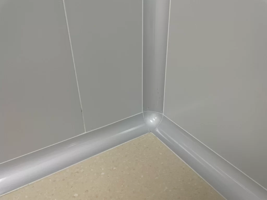 Close-up of a cleanroom wall corner constructed with aluminum profiles, featuring smooth surfaces and tight seams that ensure airtight integrity (maintaining 10-20 Pa positive pressure) and block microbial contamination in medical environments like ICUs and operating rooms.