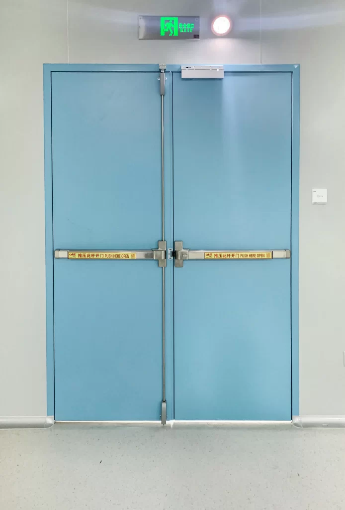 A cleanroom and medical airtight double door with emergency exit sign, blue door panel and metallic push bar, clean and bright indoor environment.