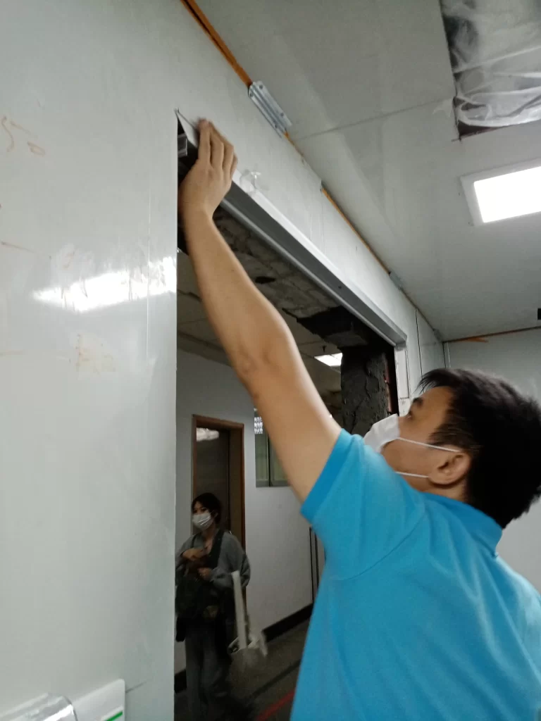  A technician performing precision alignment checks during cleanroom door installation in a facility.