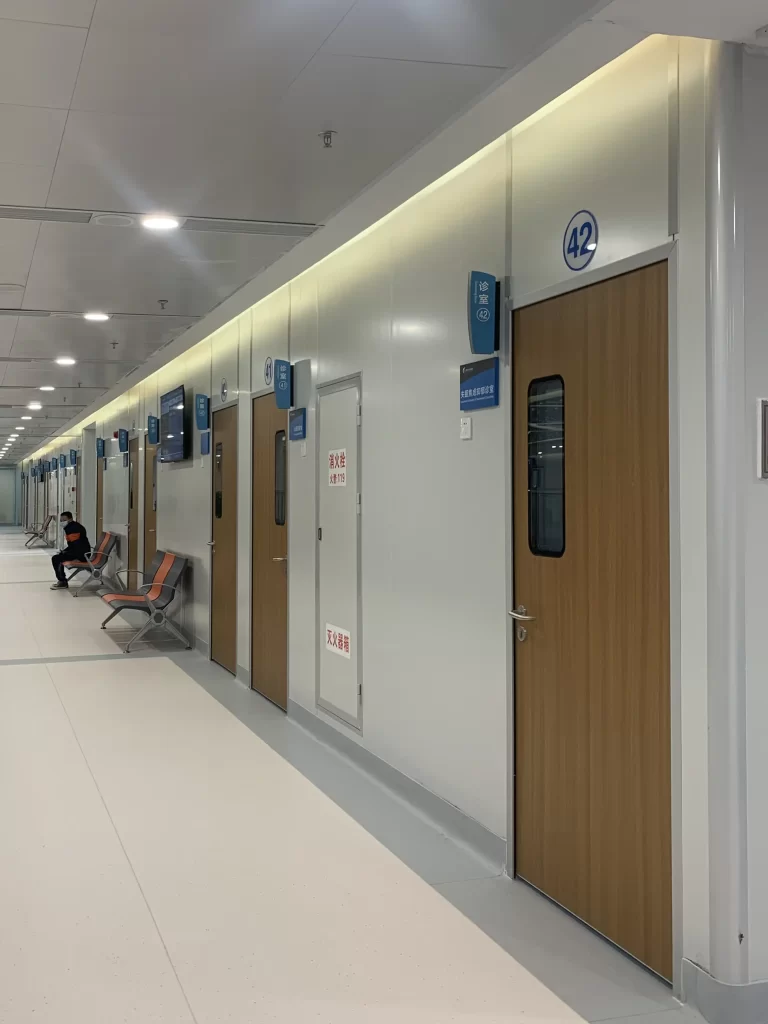Modern Medical Swing Doors with narrow vision panels lining a sterile hospital corridor for patient rooms.