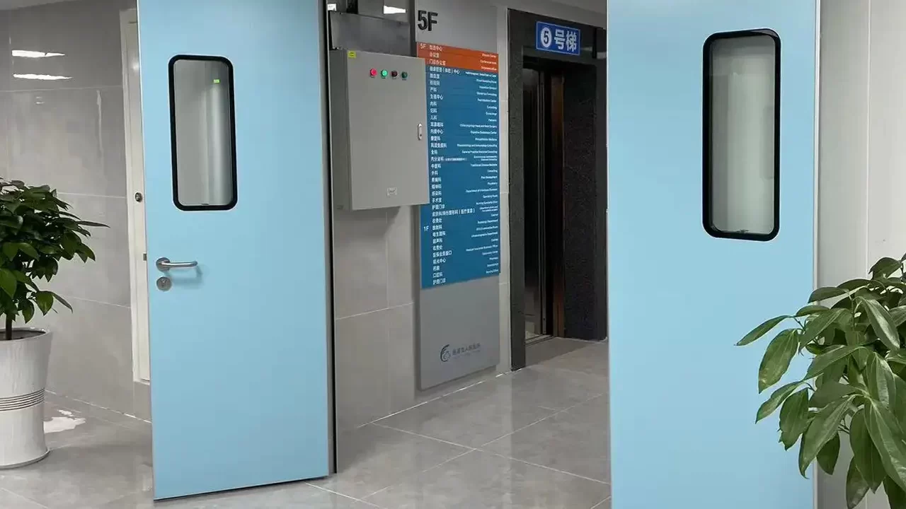 Open light blue hospital double doors revealing a polished tile corridor, elevator lobby, and floor directory sign.