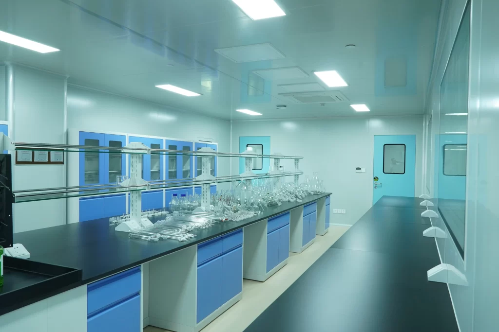 Modern laboratory with FDA compliant cleanroom doors, blue cabinets, black countertops, and scientific glassware equipment.