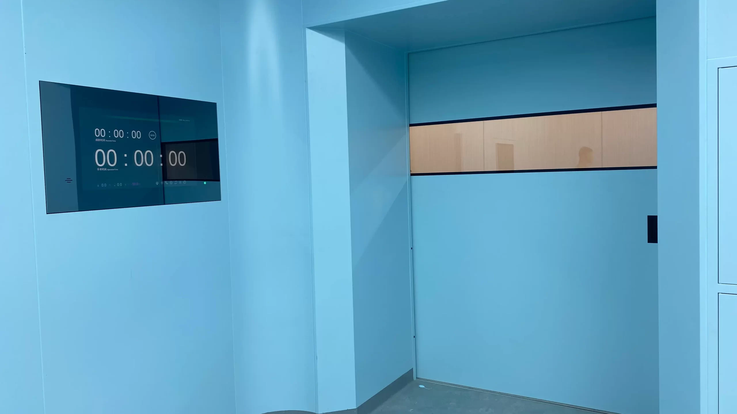 Cleanroom interior featuring an automatic sliding door with a horizontal window and a digital control panel on the wall.
