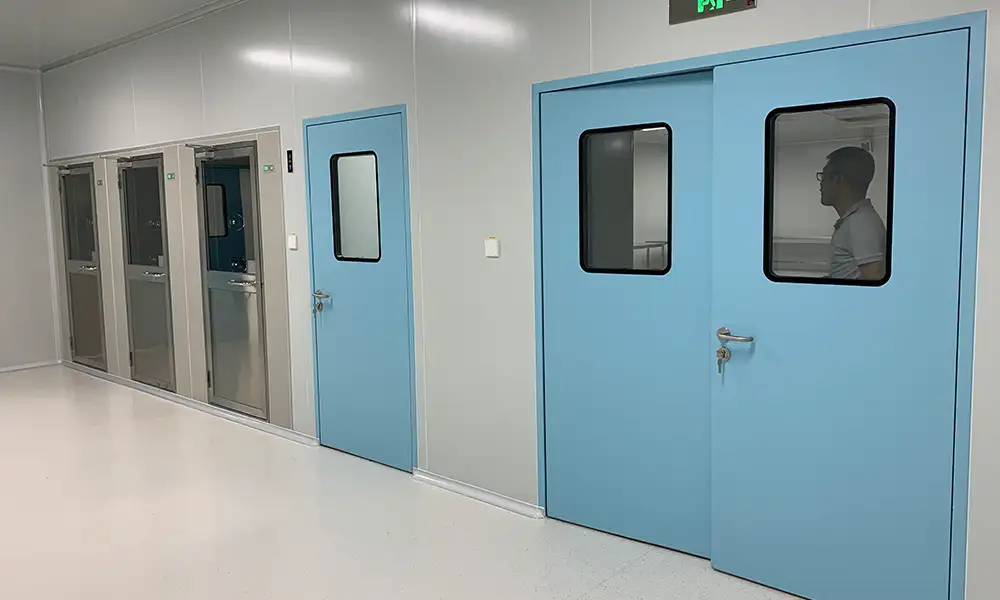 Corridor view of multiple blue GMP-compliant cleanroom swing doors with observation windows.