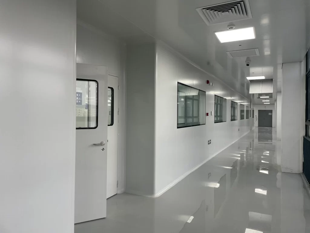 Hospital double doors in a bright, sterile cleanroom corridor with reflective floors, observation windows, and integrated lighting in a healthcare facility.