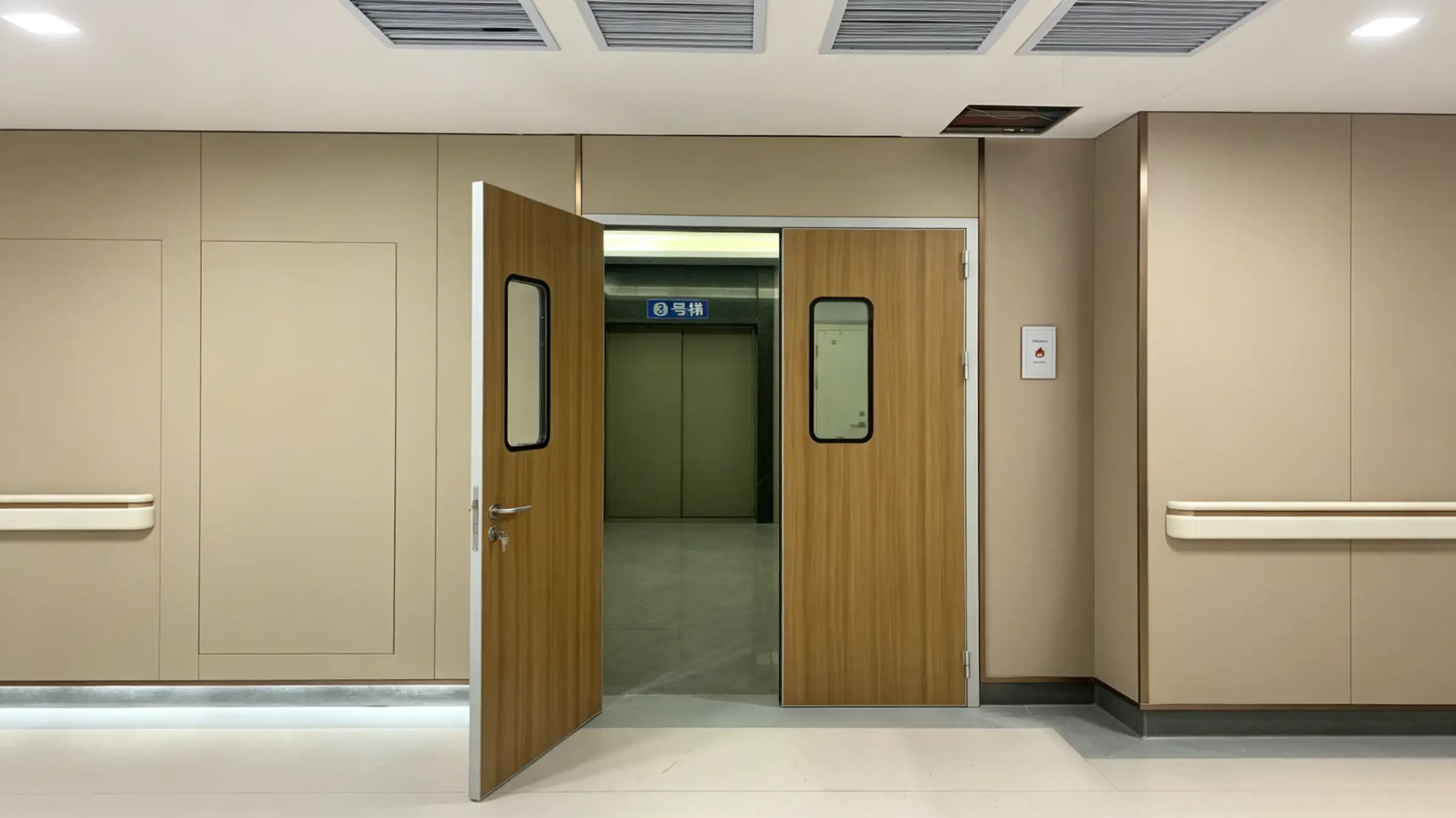 Wooden hospital double doors with glass view panels; one door open revealing elevator lobby with 