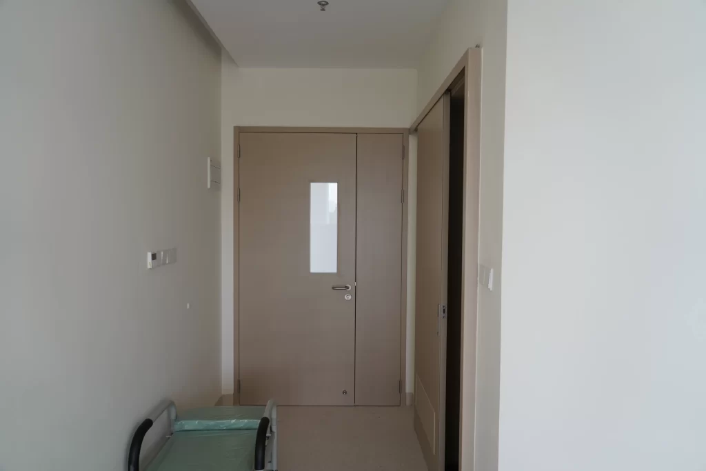 Full shot of HPL cleanroom double door in hospital gowning corridor, light wood finish with observation window, matching Grade C/D cleanroom personnel passage scene.