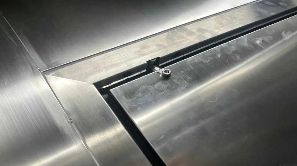 Macro close-up of stainless steel cleanroom door hinge, full welded metal frame structure, tight seamless edge sealing for VHP disinfection resistance.