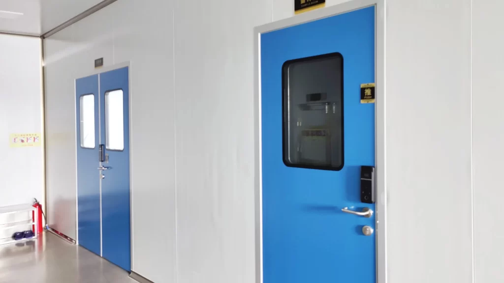 Realistic GMP pharmaceutical cleanroom interior with Cleanroom pass doors, single blue personnel swing door with access lock and double-leaf material pass door, seamless white wall, stain-resistant clean floor.