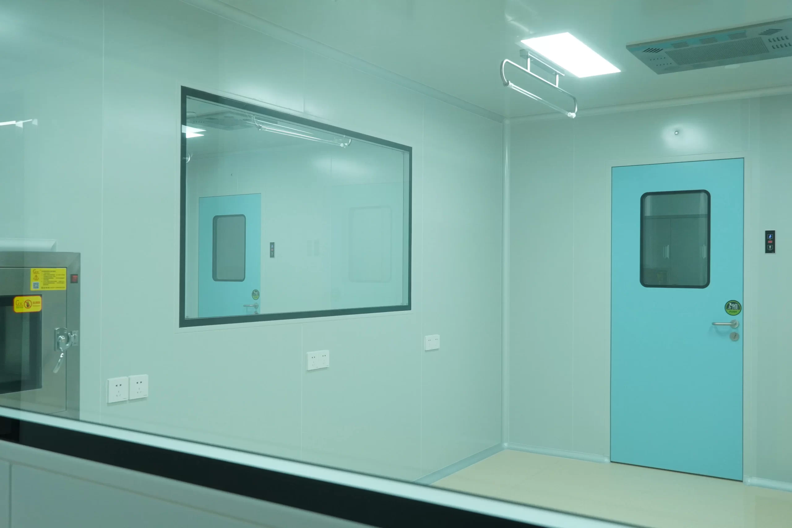 Food Processing Doors: Light blue sanitary swing door with observation window in food manufacturing cleanroom, smooth non-porous wall panels, sterile high-care hygiene production zone interior.