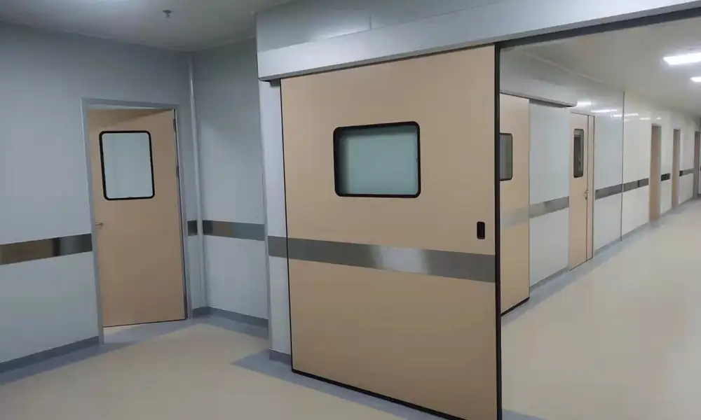 Cleanroom corridor with beige hermetic sliding self-closing door and swing cleanroom doors, controlled environment for pharmaceutical and hospital contamination control.