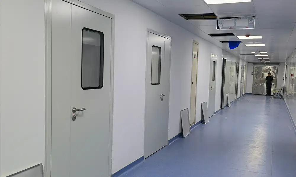 Photorealistic long cleanroom corridor lined with light gray impact resistant hygienic steel swing doors with rectangular observation windows, blue sterile vinyl flooring, modular white wall panels