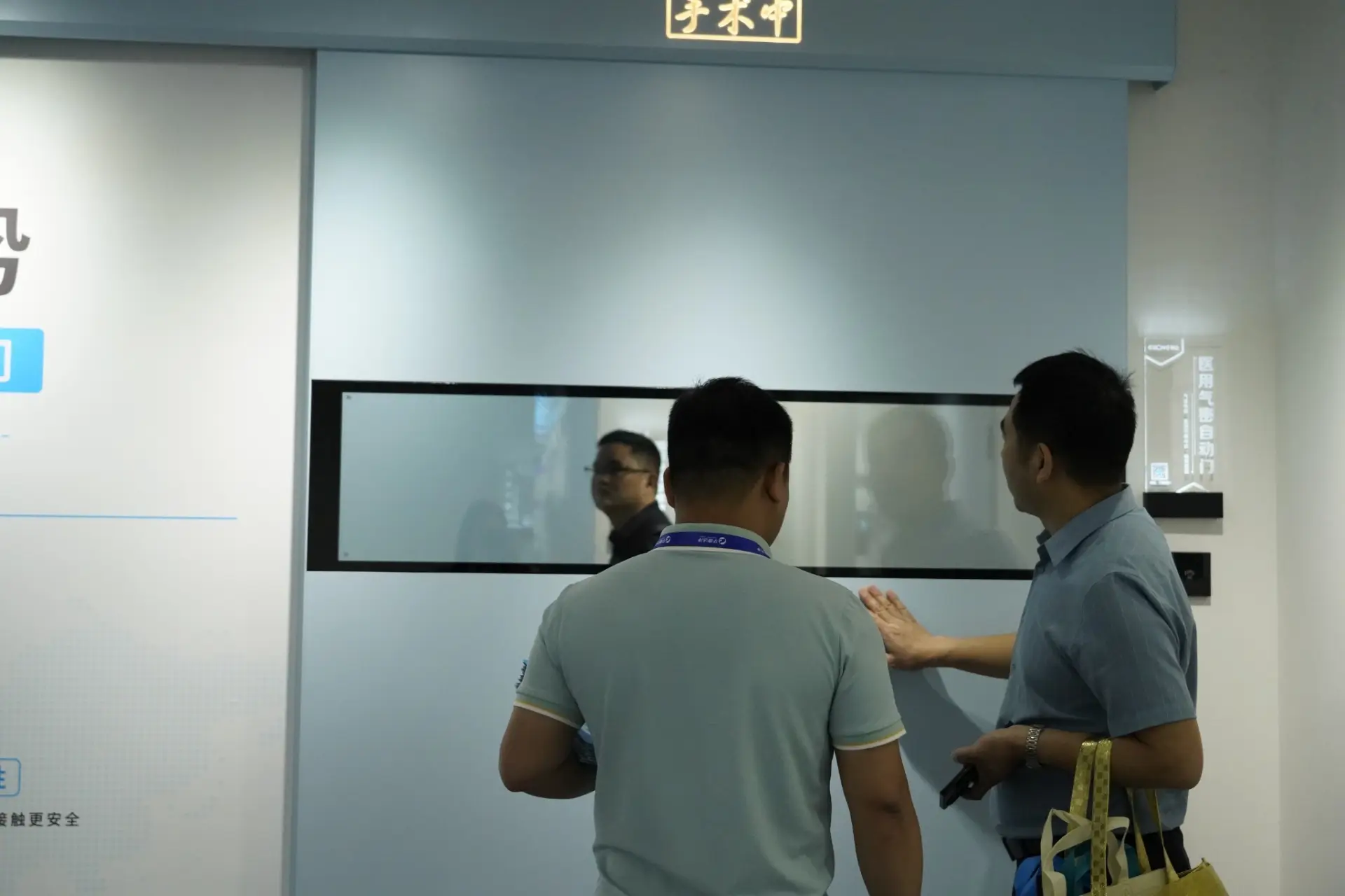 Visitors inspecting an E-ZONG light blue automatic hermetic sliding door with a narrow vision window panel designed for hospital operating rooms and cleanroom environments.