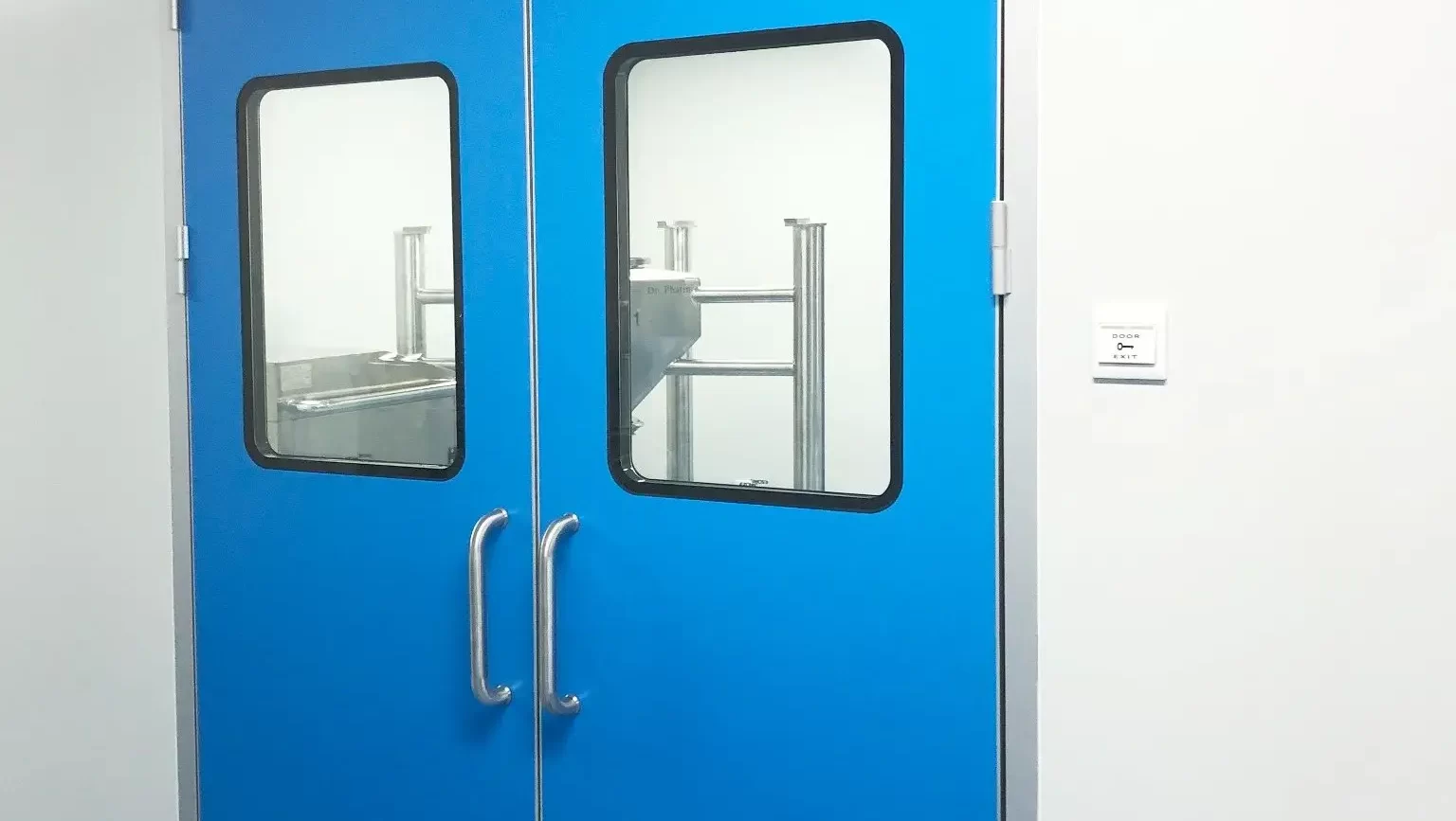 E-ZONG blue double-leaf automatic swing cleanroom door featuring large observation windows, stainless steel push handles, and top-mounted automatic door operators installed in a pharmaceutical production facility