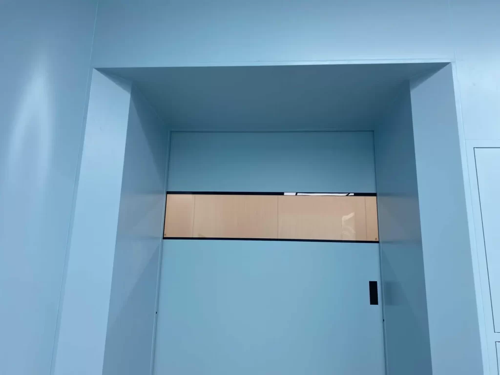 Close-up of an E-ZONG airtight sliding cleanroom door leaf featuring a rectangular flush-mounted vision window and recessed wall frame