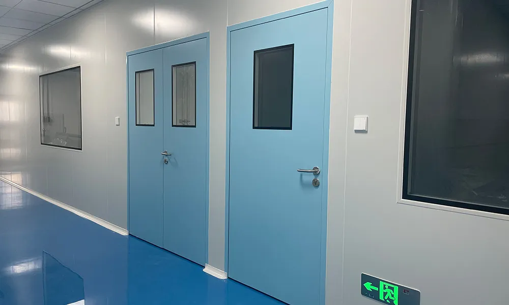 Blue steel cleanroom doors with double glass vision panels installed in a pharmaceutical cleanroom corridor