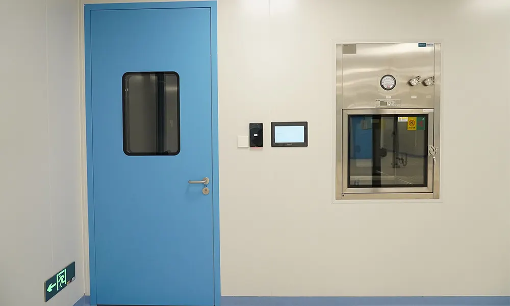 Blue steel cleanroom door with observation window installed next to a stainless steel pass box