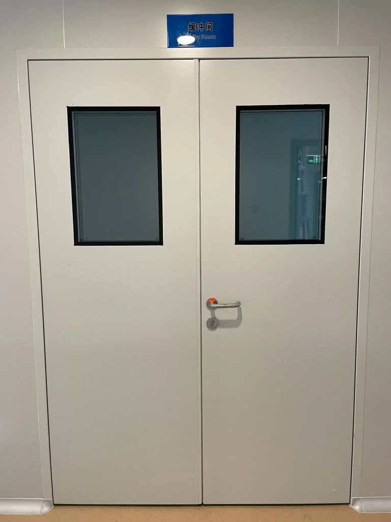 E-ZONG white double-leaf swing cleanroom door with double-glazed flush vision panels and stainless steel lever handle, installed at a cleanroom buffer room entrance