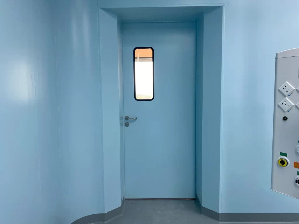 E-ZONG light blue cleanroom single swing door featuring a flush-mounted narrow vision panel and stainless steel handle in a sterile cleanroom corridor