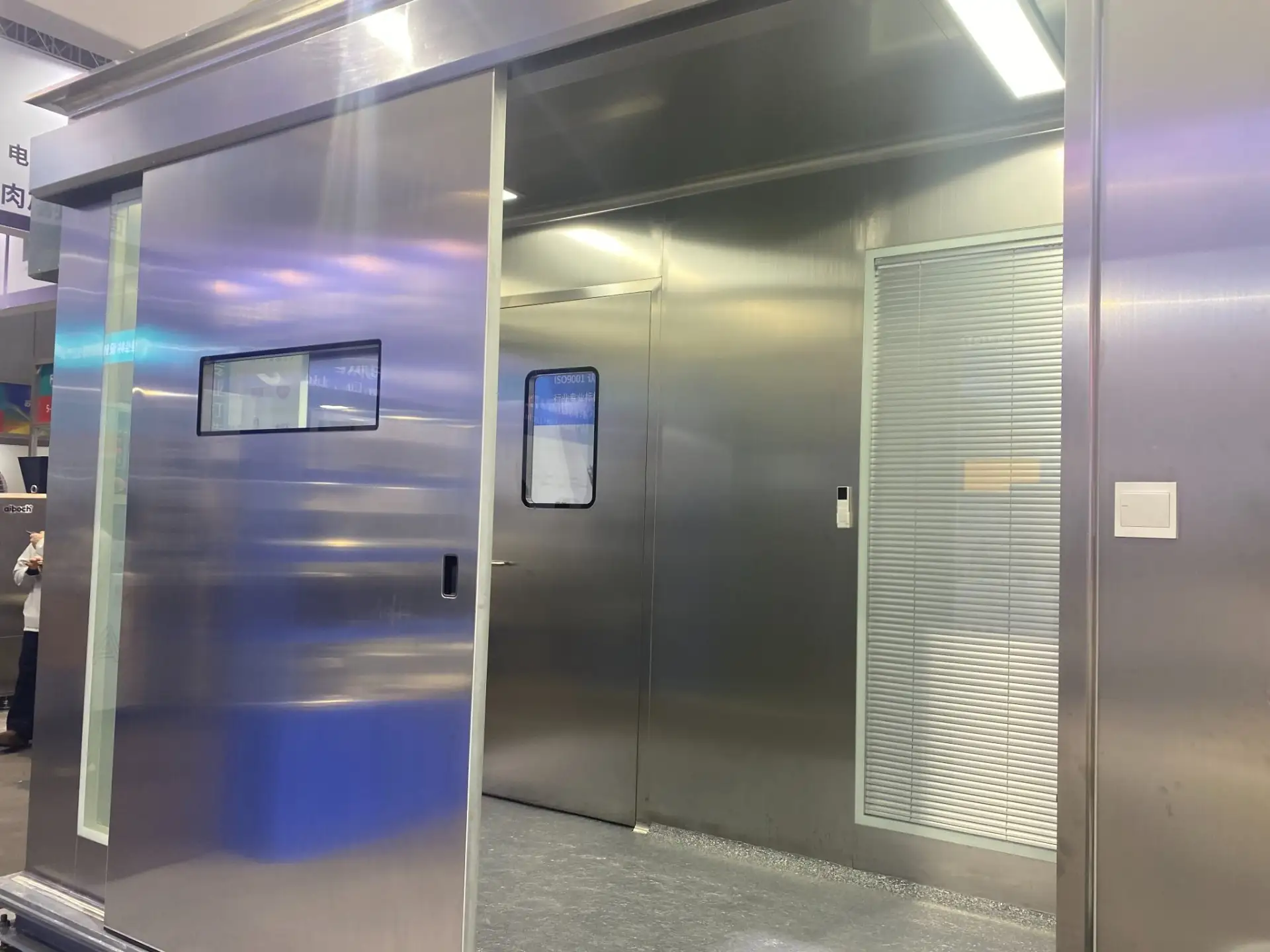 E-ZONG stainless steel automatic sliding cleanroom door featuring a vision panel window, installed along a stainless steel wall panel system with an internal swing door and blind window.